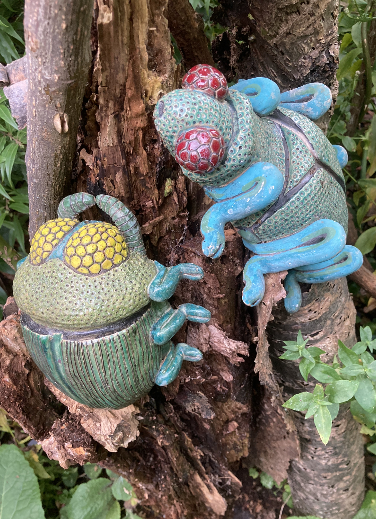 Conceptual ceramic interpretations of wood boring beetles against the backdrop of a decaying beetle inhabited cherry tree stump.